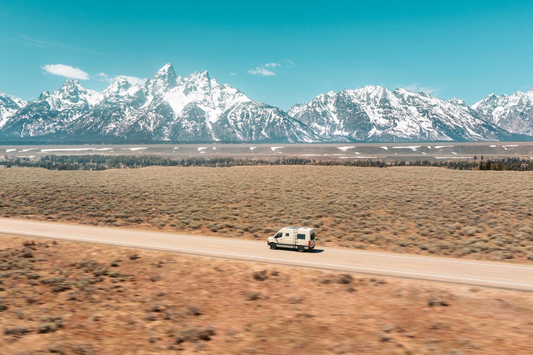 Aerial View of a Moterra Campervan Rental in Jackson, WY Traveling in Front of the Teton Range